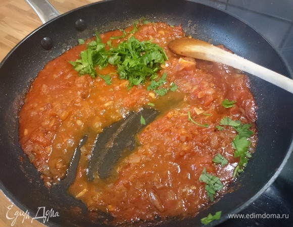 Для приготовления соуса разогрейте 1 столовую ложку оливкового масла в сковороде на среднем огне. Добавьте лук и пассеруйте, часто помешивая, до тех пор, пока он не станет прозрачным, от 2 до 4 минут. Уменьшите огонь до минимума и добавьте чеснок и соль, помешивая, в течение минуты, пока чеснок не станет мягким. Добавьте хлопья красного чили, тмин и зиру, помешивайте в течение 30 секунд, пока появится стойкий аромат. Добавьте помидоры, предварительно их измельчив, и томатный сок. Увеличьте огонь до среднего и готовьте в течение 5–6 минут, часто помешивая. Посолите и поперчите, добавьте щепотку сахара и тушите до выпаривания жидкости. Выключите огонь и добавьте кинзу. Отложите в сторону. (Соус можно хранить в холодильнике до пяти дней.)