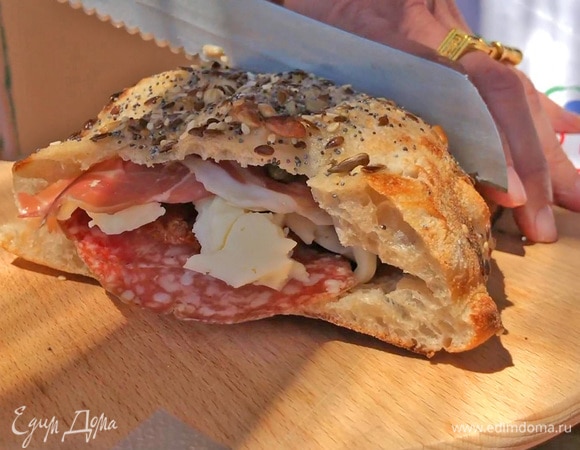 Накрыть бутерброд верхней частью фокаччи и разрезать пополам.