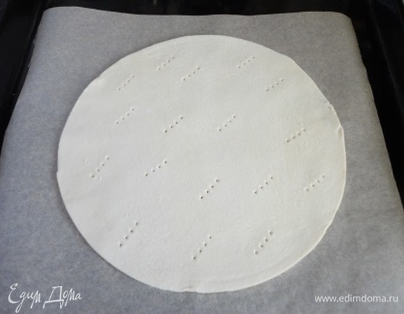 Каждую пластину размороженного слоеного теста разделить на две части, раскатать прямо на бумаге для выпечки и вырезать круги диаметром 18–20 см. Обязательно наколоть вилкой и выпекать в духовке при температуре 180–200°C до светло-золотистого цвета. Время контролируйте по своей духовке: 7–10 минут. Оставшиеся обрезки также запеките. Будем использовать их для оформления.