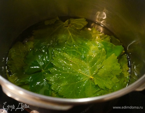 Виноградные листья хорошо промыть проточной водой. Затем ненадолго оставить в большой миске с водой, чтобы отошел песок и грязь. В кастрюле вскипятить воду, убавить огонь до минимума и партиями класть в горячую воду листья (штук по 10) на 1–2 минуты. Листья полностью должны поменять цвет. Затем достать и остудить. Если у вас мороженые листья, то просто разморозить, а если маринованные, то замочить их в воде на некоторое время, чтобы убрать лишнюю соль.