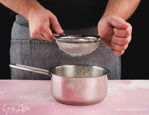 Добавьте просеянную сахарную пудру. Поставьте сотейник на средний огонь. При постоянном помешивании доведите смесь до кипения и варите в течение 10 минут.