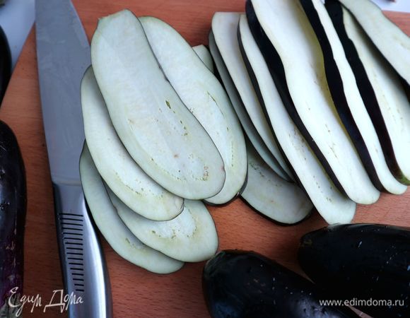 У баклажанов срезать плодоножки, нарезать вдоль тонкими пластинами.