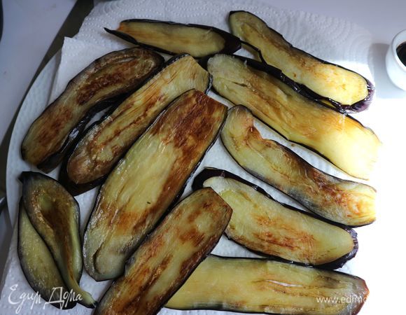 На разогретой сковороде с добавлением масла обжарить баклажаны до золотистой корочки. Баклажаны должны быть мягкими, эластичными. Положить на бумажное полотенце.