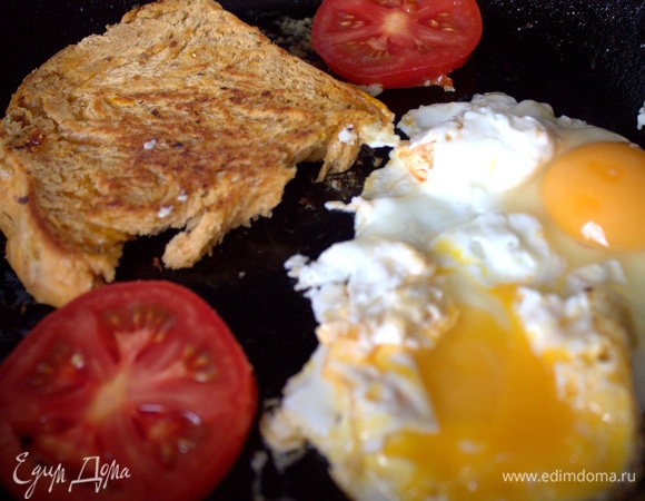 Обжаривает домашний хлеб на сливочном масле, рядом классическая глазунья.