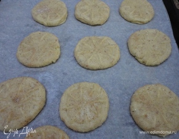 Скатать 10 шариков, руками слегка приплюснуть их и обмакнуть в смеси сахара с корицей. Выложить на противень, выстланный бумагой, и придавить стаканом с резным дном.