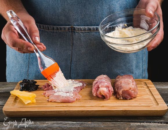 Положите мякоть куриных бедрышек на рабочую поверхность, смажьте смесью майонеза с чесноком.