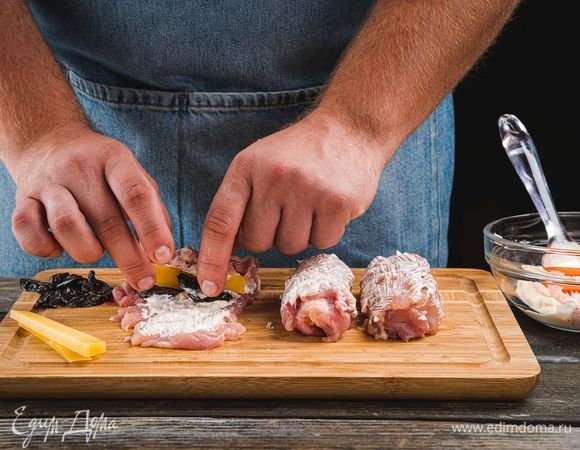 С одного края положите несколько брусочков чернослива и сыра. Заверните мякоть бедрышек в рулетики. Сверху каждый рулетик смажьте майонезом.