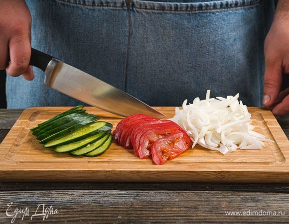 Помидоры, огурцы и зелень промойте и обсушите. Огурцы и помидоры нарежьте продолговатыми брусочками. Лук нарежьте перьями.