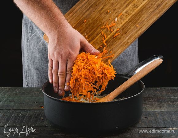 Приготовьте подливу. Измельчите лук, натрите на терке морковь. Лук поджарьте в глубокой сковороде до прозрачности, далее добавьте к нему тертую морковь. Продолжайте обжаривать на медленном огне.