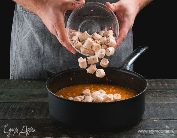 Положите нарезанные колбаски в сковороду, посолите, поперчите. Добавьте лавровый лист, чеснок и измельченную зелень петрушки. Тушите колбаски с фасолью еще 3 минуты и снимайте с огня.