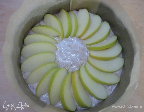 Дно формы диаметром 18 см застелить пекарской бумагой, бока смазать сливочным маслом или тоже выстелить пекарской бумагой. Выложить тесто в форму и сверху украсить яблочными пластинками.