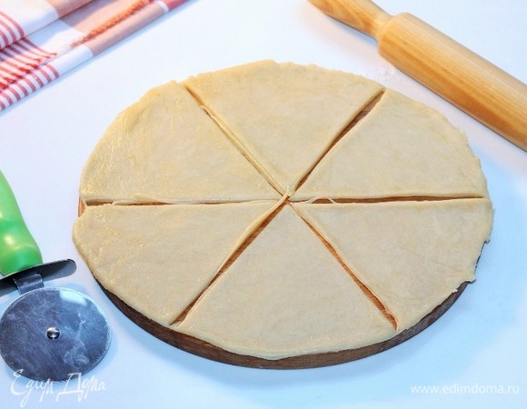 Припыляем столешницу мукой. Достаем по 1 части теста из холодильника и раскатываем в круг диаметром 24 см. Делим круг на 6 частей.