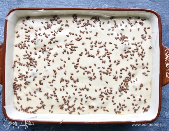 Залить оставшимся тестом, слегка постучать формой о столешницу, чтобы тесто распределилось равномерно, и посыпать верх льняным семенем.