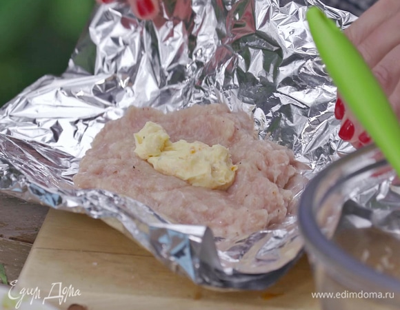 На двойной слой фольги выложить получившийся фарш. Сверху — один из видов ароматного масла. Свернуть фарш в рулет при помощи фольги так, чтобы масло оказалось внутри котлеты (при необходимости добавить фарша). 