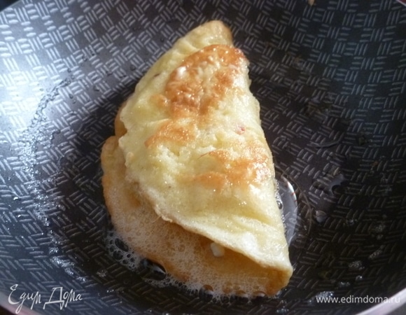 Через полминуты аккуратно завернуть один край на другой и слегка придавить ложкой, придавая форму полумесяца.