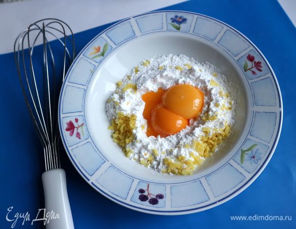 В сахарной пудре сделать углубление в центре и добавить желтки, добавить натертую на мелкой терке лимонную цедру.