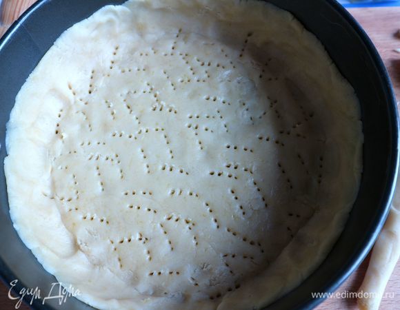 От теста отделить часть на бортики. Донышко формы смазать слегка сливочным маслом и посыпать мукой. Основную часть теста раскатать скалкой на донышке формы до толщины около 0,5 см. Сделать бортики из теста. Удалить излишки теста с бортов, эти обрезки теста понадобятся для формирования декоративного орнамента.