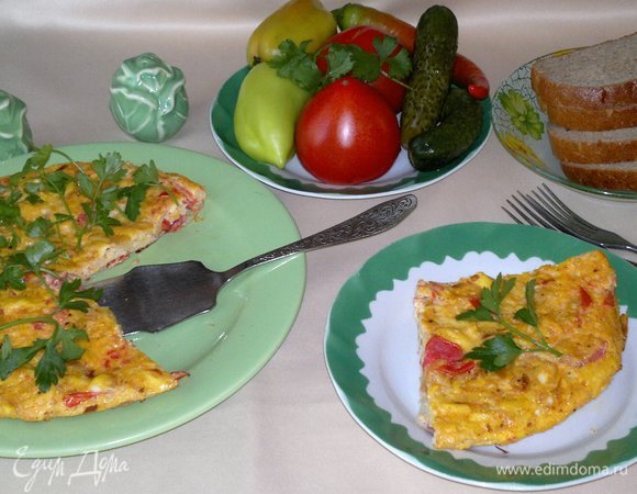 Омлет с луком и помидорами готов. Переложить его на блюдо. Украсить его зеленью петрушки.