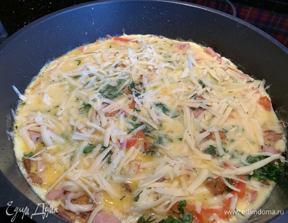 Посыпьте рубленой зеленью и натертым на крупной терке сыром. Убавьте огонь и жарьте до готовности.