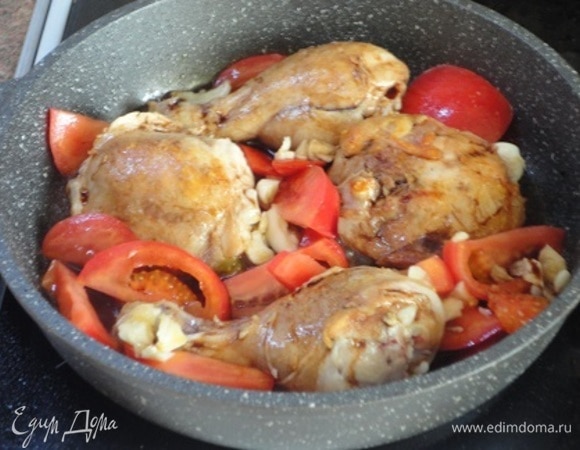 Окорочка в сковороде полить бальзамическим уксусом, добавить чеснок и нарезанные помидоры. Хорошо прогреть все вместе и снять с огня. Сверху на куриные бедра выложить кружочки помидоров. И вставить сковородку с птицей в разогретую духовку. Печь 15 минут.
