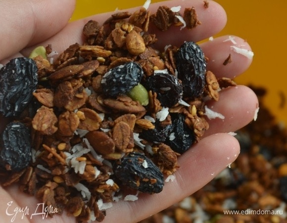 Смесь равномерно распределить по противню и выпекать 40 минут при 150°C. Каждые 10 минут перемешивать. Добавить изюм и кокосовую стружку. Подавать гранолу с йогуртом, мягким творогом или молоком. По желанию можно добавить фрукты и ягоды.