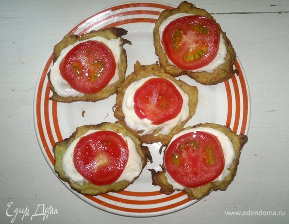 На сметану выложить кружки помидоров.