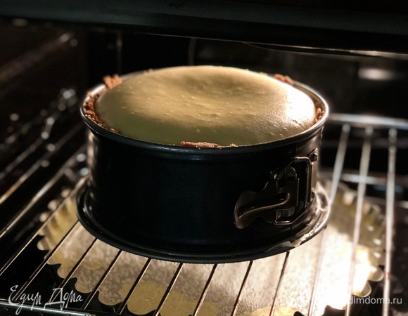 В духовку поставьте противень с емкостью с водой. А над ним — решетку. На решетку ставьте чизкейк и выпекайте в разогретой до 160°С духовке примерно 1,5 часа. Во время выпекания он поднимется, может немного треснуть. Когда поверхность станет слегка коричневойт, а деревянная палочка при протыкании будет сухой (комочки на ней могут оставаться, имеется в виду, что она не будет вся мокрая и в креме), это будет означать, что чизкейк готов!