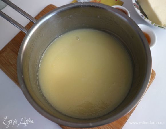 Варим яично-молочный сироп. Смесь поставить на огонь, довести до кипения, все время перемешивая смесь. Варить смесь на маленьком огне примерно 5 минут после закипания, до загустения, постоянно перемешивая. Рекомендуемая температура, которую достигает смесь при приготовлении 104–105°C. Сироп будет похож по консистенции на сгущенное молоко — умеренно тягучая, однородная смесь. Перелить смесь в другую посуду, процедив, дать полностью остыть. Во время остывания перемешивать периодически, чтобы сироп не покрылся пленкой. Сироп обладает влажным блеском. Затянуть миску со смесью пищевой пленкой. Можно на небольшое время убрать сироп в холодильник, минут на 15, требуется температура смеси 20–22°C.
