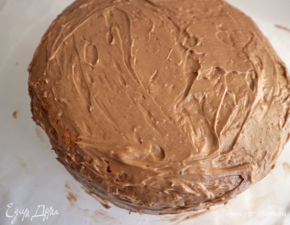 Положить на него верхний корж таким образом, чтобы нижняя часть коржа была вверху, эта часть более ровная. Нанести шоколадный крем сверху, обмазать этим кремом бока торта. Убрать в холодильник на 20–30 минут.