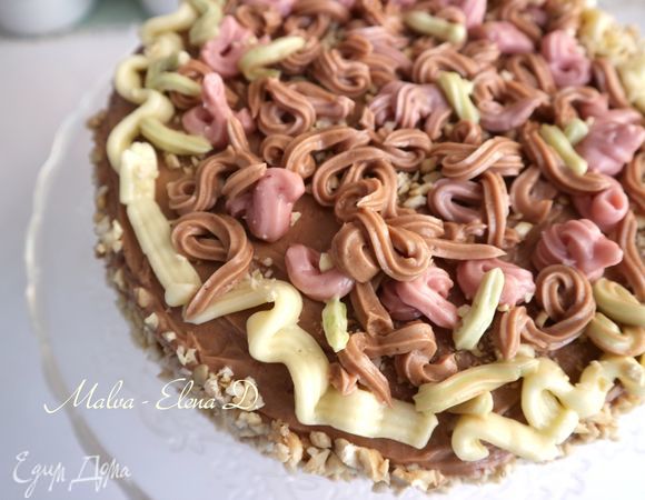  Нанести орехи (50 г) на бока торта. Оформить верх торта c помощью кондитерского шприца кремом разных цветов, можно использовать цукаты.