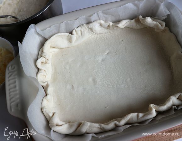 Раскатать тесто, форму (дно и борта) выстелить бумагой для выпечки, положить раскатанное тесто, сформировав также бортики из теста.