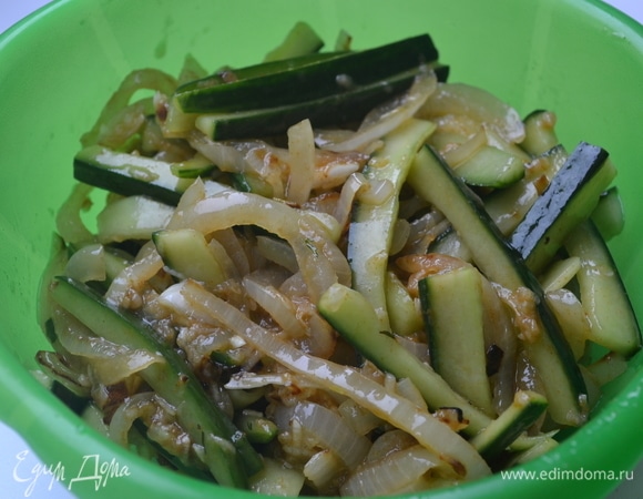 Репчатый лук нарезать полукольцами и обжарить на растительном масле. Половину лука, 1 столовую ложку яблочного уксуса, щепотку сахара и щепотку острого перца добавить к огурцам и перемешать.
