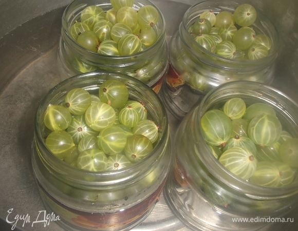 В большую кастрюлю налить воды. Поставить баночки с крыжовником. Вода должна доходить до плечиков банки. Прикрыть крышками. Довести воду до кипения. Убавить огонь.