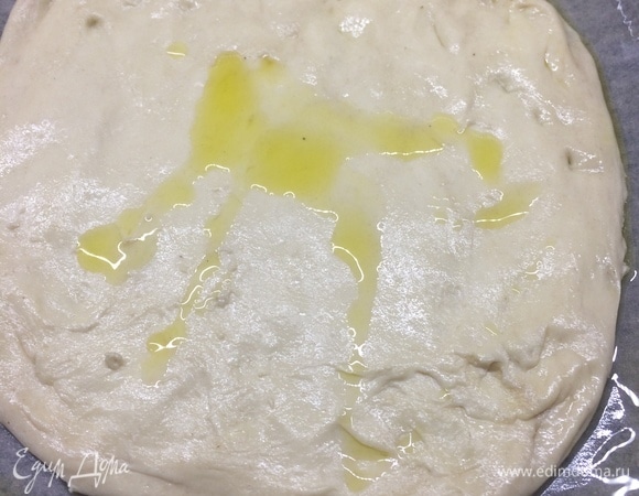 Противень выстилаем бумагой, смазываем растительным маслом и на него выкладываем тесто, придавая руками форму прямоугольника. Смазываем его оливковым маслом.