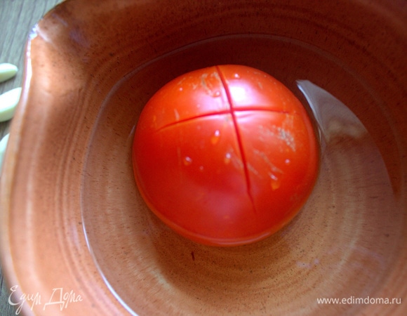 Ошпарить томат и затем снять кожицу.