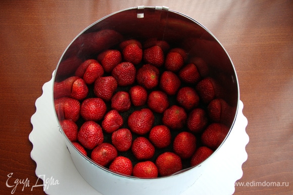 Уложить клубнику на бисквит: половинки — по краям, целые ягоды — внутрь.