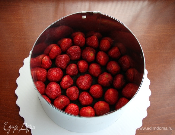 Уложить клубнику на бисквит: половинки — по краям, целые ягоды — внутрь. Так муссовый торт с клубникой получится красивым и аккуратным.