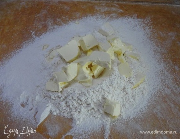 Муку просеять на рабочую поверхность. Сделать небольшое углубление, всыпать в него сахарный песок, соль и сливочное масло кусочками. Порубить с помощью ножа до состояния крошки.