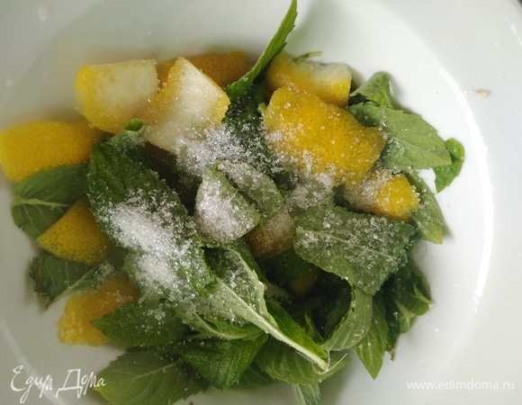 Листья мяты вымыть. С лимона снять цедру и выжать сок. Соединить в миске мяту, цедру и сок, насыпать ложку сахара и хорошо размять.