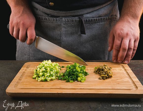 Нарежьте огурец мелким кубиком. Лук помойте и мелко нарежьте, также нарежьте и каперсы.