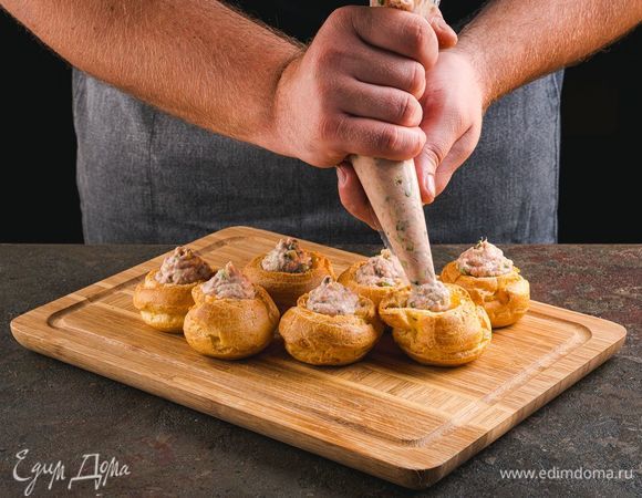Разрежьте профитроли пополам. Выложите смесь в кондитерский мешок и добавьте в половинку профитроли.