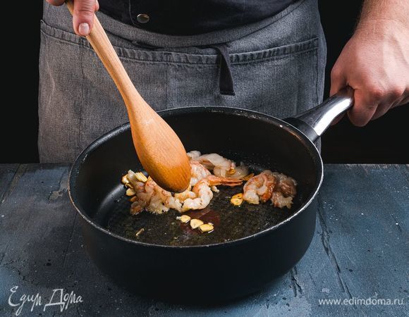 В сковороду добавьте растительное масло и мелко нарезанный чеснок. Обжарьте чеснок до золотистого цвета. Добавьте в сковороду креветки и обжаривайте их до готовности 2–3 минуты.