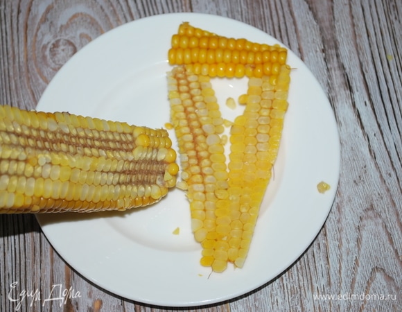 Очистите ножом початок вареной кукурузы.