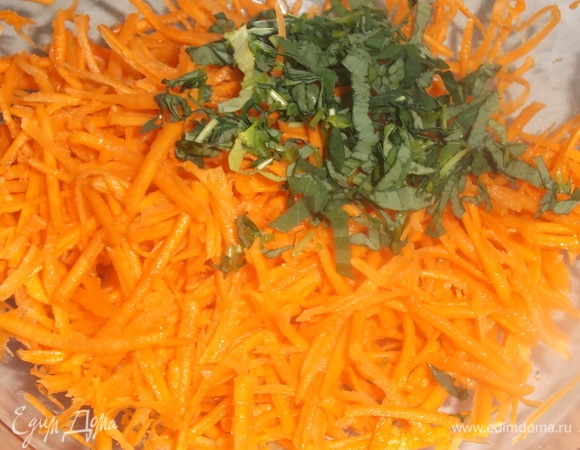 Морковь натереть на терке для корейской моркови. Посолить. Слегка помять. Добавить нарезанные листья. Перемешать. Добавить растительное масло. Накрыть салатник крышкой. Дать настояться в течение часа.