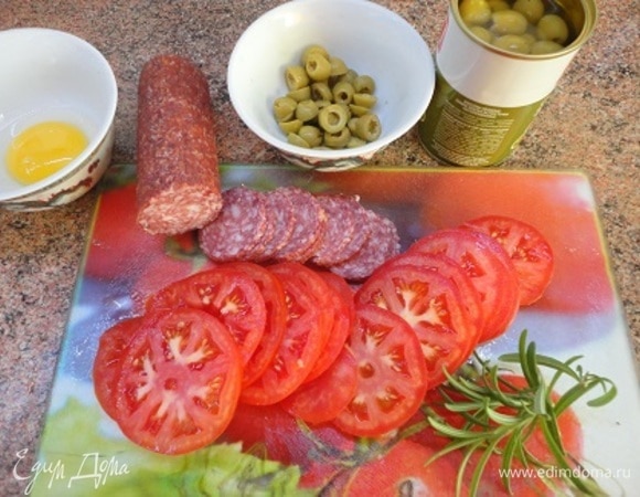 Помидоры, салями и оливки нарежьте кружочками. Включите духовку на разогрев до 200°C.