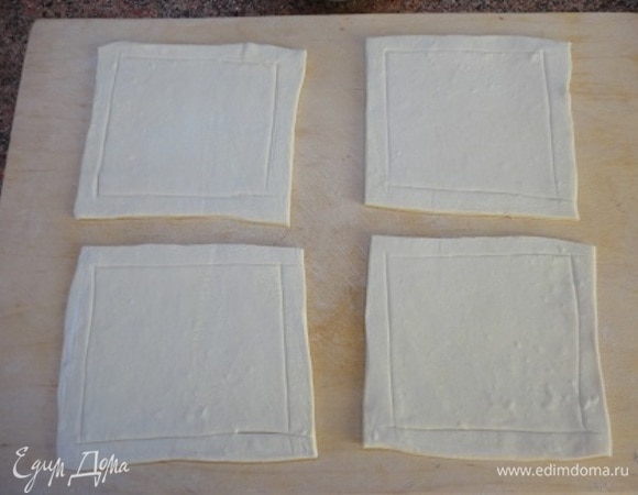 Каждый лист слоеного теста раскатать и разрезать на 4 части. По краю, отступив на 1 см, острым ножом проведите линии, не прорезая до конца. Переложите на лист с пекарской бумагой.