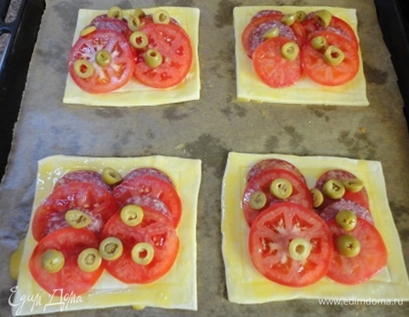 Слегка сбрызните каждый прямоугольник оливковым маслом и нарвите листочки базилика или розмарина. Затем выложите помидоры, чередуя их с салями, и сверху — оливки. Поперчите, еще раз сбрызните оливковым маслом. Края теста смажьте яйцом.