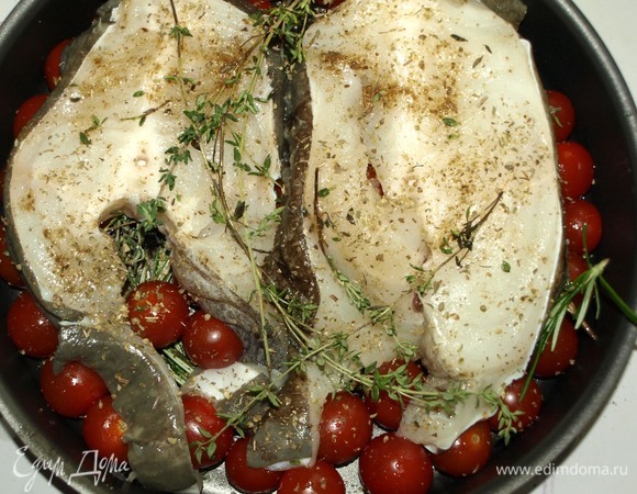Выкладываем на помидоры черри и пряные травы стейки зубатки с тимьяном. Посыпаем сухим орегано. Отправляем в заранее разогретую до 180°C духовку на 30–35 минут.