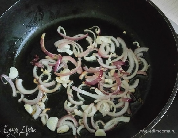 Пока перловка доходит до полной готовности, приготовьте заправку: очищенный репчатый красный лук нарежьте полудольками, обжарьте в небольшом количестве оливкового масла (лук должен остаться хрустящим). Отложите готовый лук в миску.