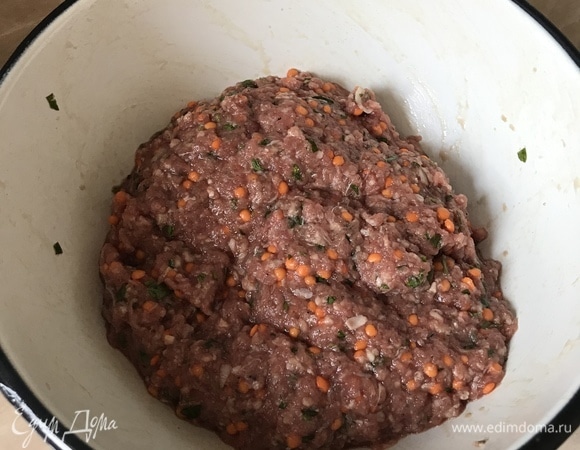 В блендере измельчить 1 головку лука, 2 зубчика чеснока и петрушку. В миске смешать фарш, измельченный лук с чеснок и зеленью, сырую чечевицу, соль, перец. Хорошо все перемешать.